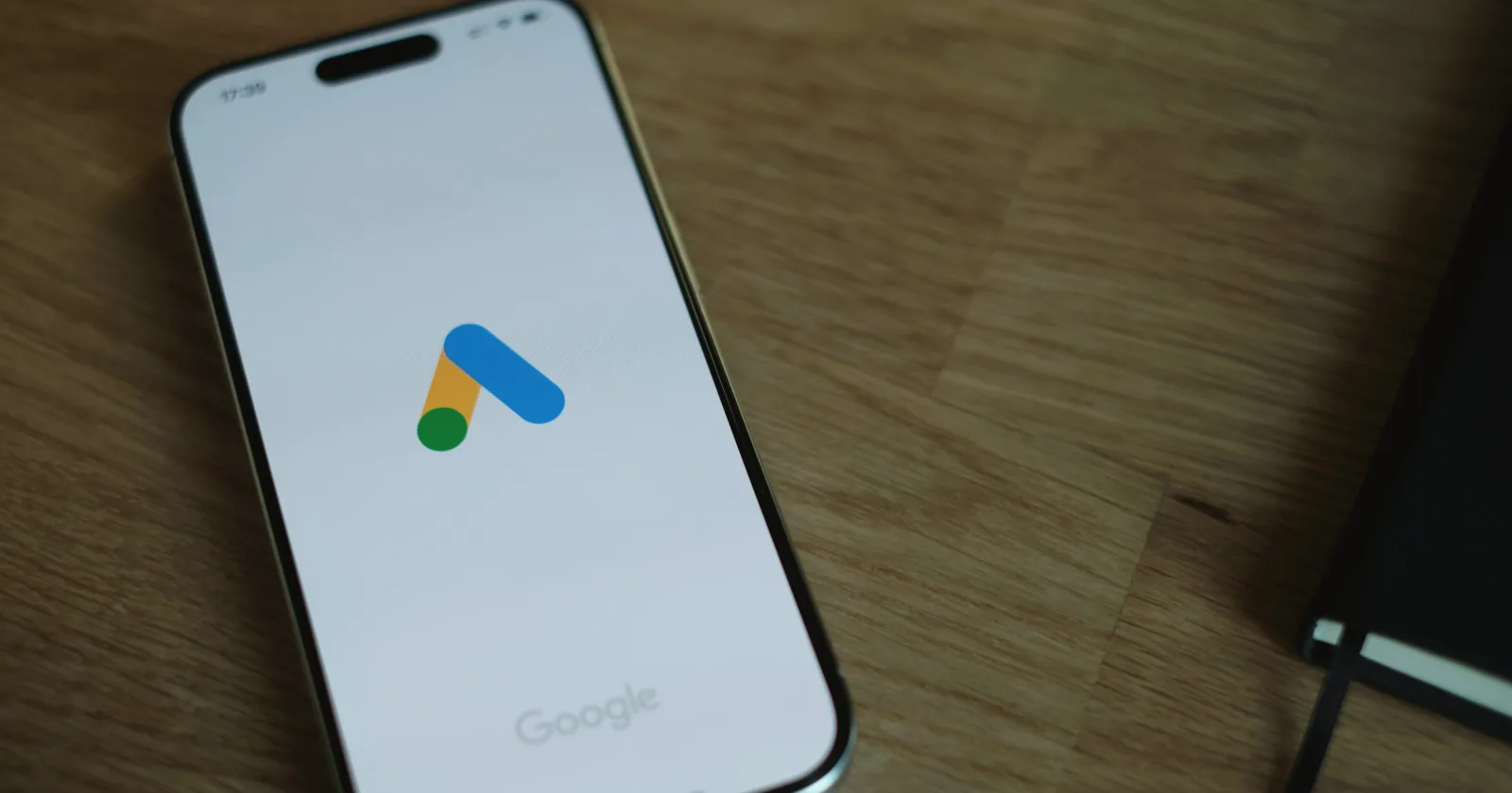 Móvil con la app de Google Ads sobre una mesa de madera: el trabajo de un especialista SEM